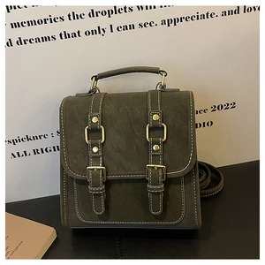 Detail of olive green mini crossbody bag with contrast stitching and gold buckles
