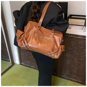 Detail of vintage brown large PU leather tote with buckle straps and side flap pockets