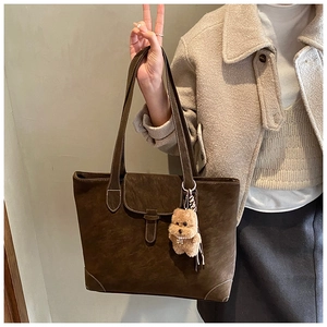 Detail of dark brown vintage tote bag with contrast stitching and teddy bear charm