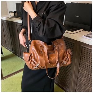 Detail of vintage brown tote bag featuring side pockets and adjustable shoulder strap