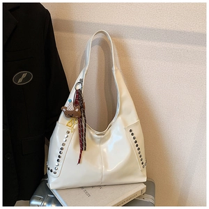 Détail du sac hobo blanc crème en similicuir avec rivets argentés et charme d'ours