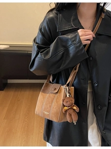 Retro brown bucket bag with top handle and crossbody strap featuring a plush bear charm