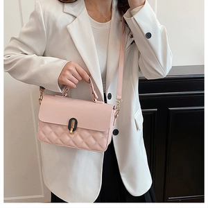 Detail of quilted cherry pink crossbody bag with a distinctive black-gold metal twist lock