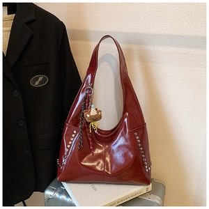 Gros plan du sac hobo bordeaux brillant avec rivets argentés et charme d'ours brun