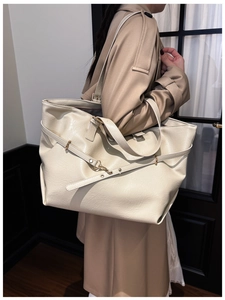 Dettaglio di una grande borsa tote in pelle bianco crema con texture elegante e hardware dorato