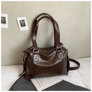 Close-up of retro brown tote bag featuring glossy wrinkled texture and reinforced stitching