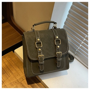 Close-up of vintage dark green faux leather backpack with metallic buckles and stitching