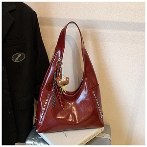 Détail du sac hobo en cuir verni rouge foncé avec rivets argentés et charm ours