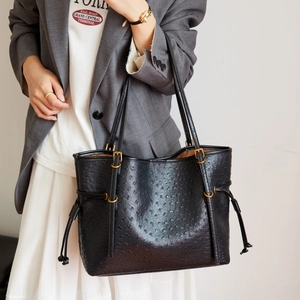 Detail of black ostrich-embossed tote bag with golden hardware and chic textured finish