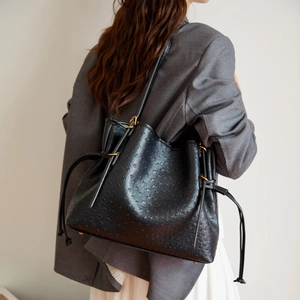 Close-up of black ostrich embossed leather tote bag with gold metal hardware details