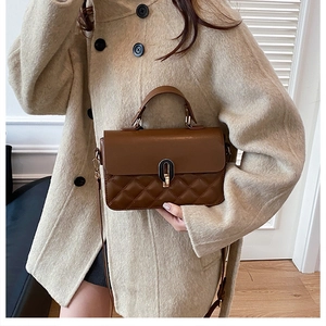 Close-up of quilted pattern and gold oval twist lock on a brown faux leather handbag