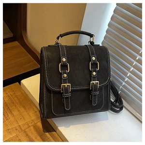 Detailed close-up of retro black faux leather backpack with white stitching and gold hardware