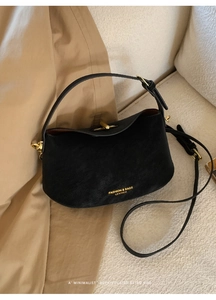 Detailed view of black retro leather bucket bag with gold hardware and shoulder strap
