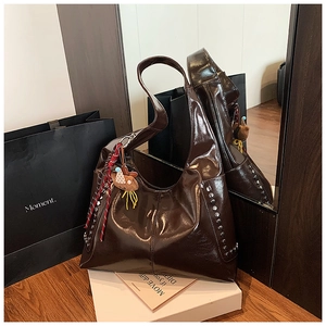 Détail d'un sac hobo marron foncé avec finition brillante et rivets argentés