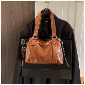 Close-up of vintage brown leather tote bag with elegant stitching on a business suit
