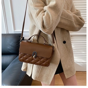 Vintage brown leather handbag with quilted stitching detail shown on a neutral wool coat