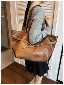 Dettaglio borsa tote marrone in pelle sintetica con fibbia metallica e tracolle