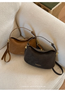 Detail of retro bucket bags in brown and grey leather with gold hardware on a sofa