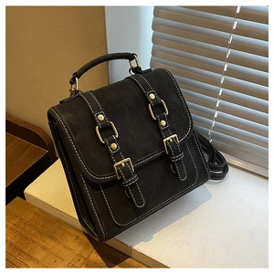 Detail view of vintage black backpack featuring white contrast stitching and gold buckles