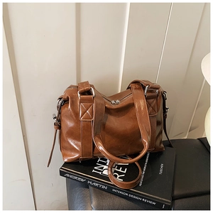 Detailed close-up of brown vintage Boston bag with silver hardware on a book decor