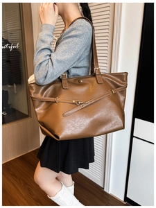 Dettaglio macro della borsa tote marrone scuro con fibbie in metallo e cinturini decorativi