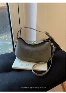 Detail of grey matte leather bucket bag featuring gold hardware and logo text