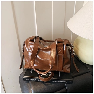Detail of vintage brown oil wax leather tote bag with silver hardware on a desk
