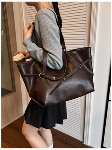 Dettaglio della borsa tote in pelle marrone scuro indossata da modella in un ambiente interno