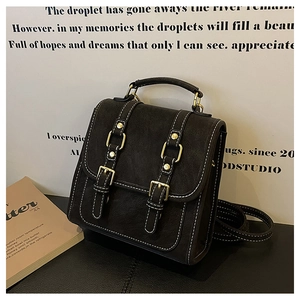 Detail of vintage matte leather backpack with white stitching and gold metal buckles