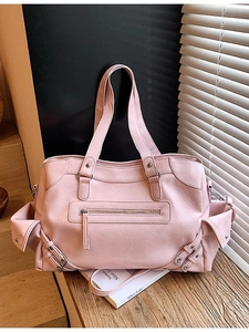Pink faux leather tote bag with side pockets and shoulder strap on a wooden desk
