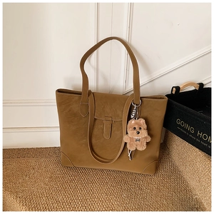 Close-up of vintage brown large capacity tote bag with cute plush puppy charm on a carpet