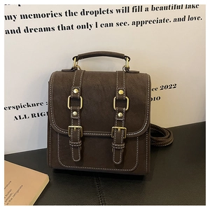 Detail view of brown matte leather backpack featuring contrast stitching and metal buckles