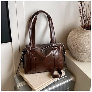 Close-up of glossy dark brown leather tote bag with silver double zippers and wide handles