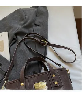 Detail view of smooth brown leather bucket bag with golden buckle and adjustable strap