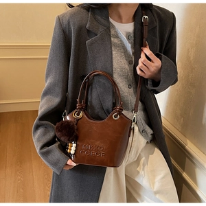 Detail of vintage brown glossy leather bucket bag with plush charm and logo embossing