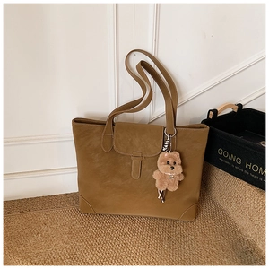 Close-up of khaki brown tote bag with suede texture and cute teddy bear pendant