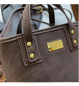 Detail of brown matte leather handbag featuring gold metal rivets and fashion logo plaque