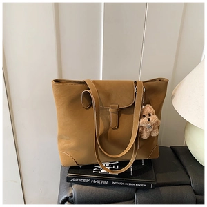 Detail of camel leather tote with decorative strap, reinforced corners and puppy charm