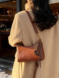 Vintage brown oil wax leather hobo bag worn by model in cafe setting with soft winter light