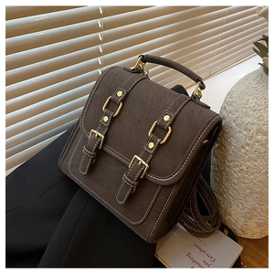 Detailed view of vintage brown matte backpack with gold studs and decorative buckles