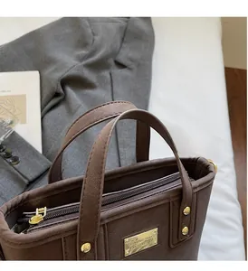 Detailed close-up of dark brown pebble leather handbag with gold zipper and hardware