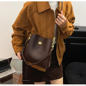 Detail of dark brown pebble leather bucket bag with gold clasp and adjustable strap