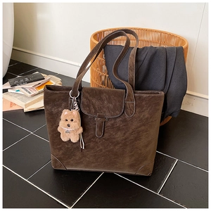 Detail of retro dark brown leather tote with metallic buckle and plush dog charm