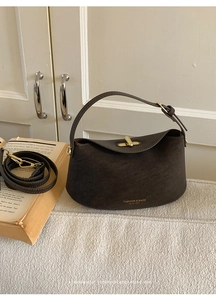 Detail of dark brown retro bucket bag with gold metal buckle and matte leather texture