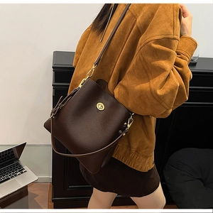 Detailed close-up of dark brown lychee grain leather bucket bag with golden twist lock