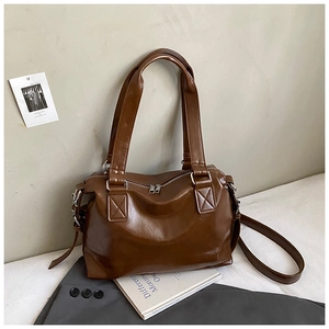 Close-up of deep brown matte leather texture and sturdy handles on a vintage Boston bag