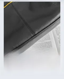 Close-up of black lychee grain leather handbag with gold zipper and fine stitching