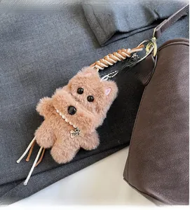 Detail of plush dog keychain with pearl necklace and TOP DOG bone tag on a handbag