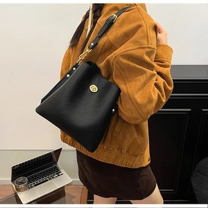 Detail of black lychee grain leather bucket bag with gold hardware and twist lock closure