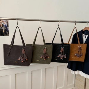 Row of four large leather tote bags in earth tones with unique dachshund dog pendants